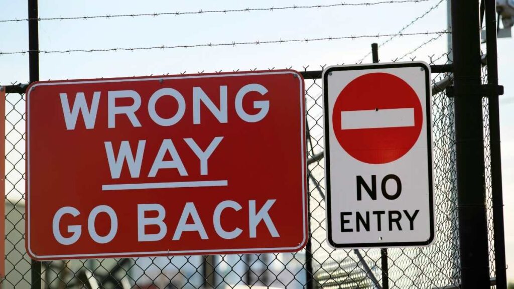 Wrong way and no entry signs displayed on a fence.