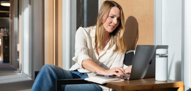 Professional working on a laptop in a modern office lounge.