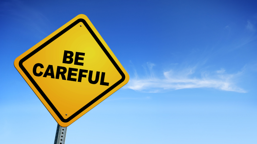 Yellow “Be Careful” warning sign against a blue sky