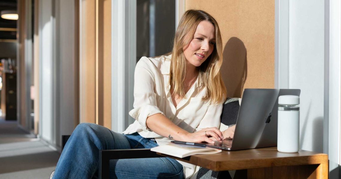 Professional working on a laptop in a modern office lounge.